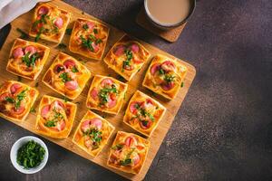 mini Pizza con salsicce, pomodori, formaggio e erbe aromatiche su un' di legno tavola su il tavolo superiore Visualizza foto