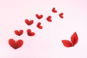 composizione di piegato rosso carta cuori e le foglie su un' rosa sfondo superiore Visualizza foto