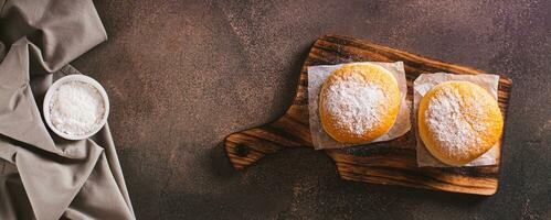 fresco ciambelle con in polvere zucchero e dolce Riempimento su un' piatto su il tavolo superiore Visualizza ragnatela bandiera foto