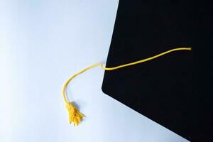 vicino su nero la laurea cappello e giallo nappa isolato su bianca sfondo foto