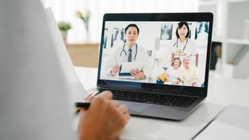 giovane dottoressa asiatica in uniforme medica bianca con stetoscopio utilizzando il computer portatile parlando in videoconferenza con il paziente alla scrivania in clinica o ospedale. concetto di consulenza e terapia. foto