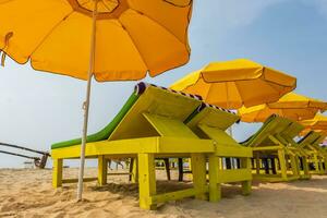 colorato di legno spiaggia ombrelli e lettini lettini su sabbioso spiaggia di oceano foto