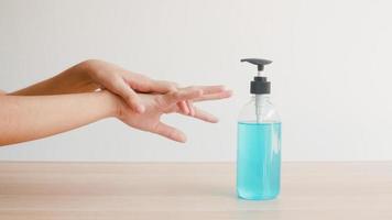 donna asiatica che usa disinfettante per le mani in gel alcolico per lavare le mani per proteggere il coronavirus. la femmina spinge la bottiglia di alcol per pulire la mano per l'igiene quando il distanziamento sociale rimane a casa e il tempo di autoquarantena. foto