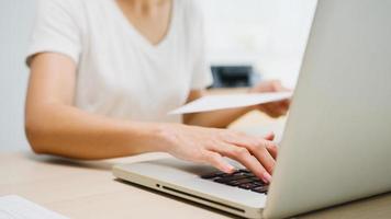 freelance giovane donna d'affari asia abbigliamento casual utilizzando laptop che lavora nel soggiorno di casa. lavoro da casa, lavoro a distanza, autoisolamento, distanziamento sociale, quarantena per la prevenzione del virus corona. foto