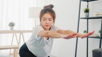 giovane donna coreana in esercizi di abbigliamento sportivo facendo allenamento e usando il laptop per guardare video tutorial di yoga a casa. formazione a distanza con personal trainer, distanza sociale, concetto di educazione online.