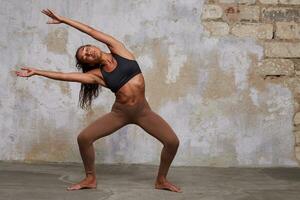 orizzontale tiro di giovane buio spellato Riccio lungo dai capelli donna conservazione sua occhi chiuso mentre godendo moderno danza lei è preparazione, isolato al di sopra di mattone parete sfondo foto