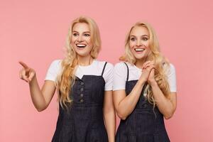 contento giovane bellissimo dalla testa bianca femmine con lungo perdere capelli mostrando loro Perfetto bianca denti mentre sorridente allegramente, in piedi al di sopra di rosa sfondo foto