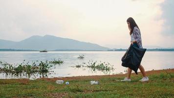 felici giovani attivisti asiatici che raccolgono rifiuti di plastica sulla spiaggia. le volontarie coreane aiutano a mantenere la natura pulita e a raccogliere la spazzatura. concetto sui problemi di inquinamento di conservazione ambientale. foto