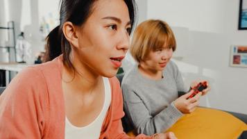 coppia di donne lesbiche lgbtq gioca a un videogioco a casa. giovane donna asiatica che utilizza un controller wireless che ha un momento felice e divertente insieme sul divano nel soggiorno. si divertono molto e festeggiano le vacanze.