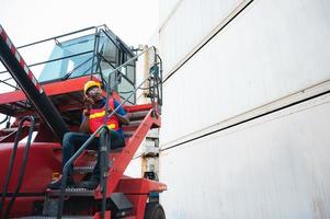 operaio caporeparto nero che lavora controllare la gru e il carrello elevatore al porto di carico dei container per caricare i container.