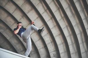 giovane che fa il salto di parkour nello spazio urbano in città soleggiata giornata estiva di primavera. foto