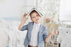 foto di uno scolaro diligente con un libro in testa che fa i compiti. lo scolaro è stanco di fare i compiti