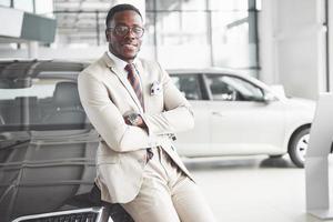 il giovane attraente uomo d'affari nero compra una nuova auto, i sogni diventano realtà foto