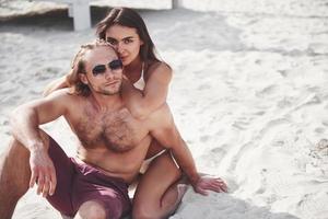 una coppia romantica sulla spiaggia in costume da bagno, bei giovani sexy foto