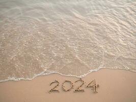 2024 anno scritto su il spiaggia nel il tramonto volta. nuovo anno 2024 concetto foto