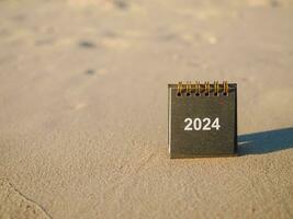 vicino su 2024 scrivania calendario su il spiaggia nel il tramonto volta. risoluzione, obiettivo, azione, pianificazione, e gestire per successo attività commerciale. foto