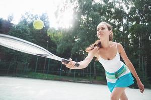 donna in abiti sportivi serve pallina da tennis. foto