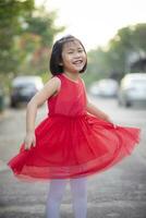 bello asiatico ragazza indossare rosso gonna vestito in movimento con felicità viso all'aperto foto