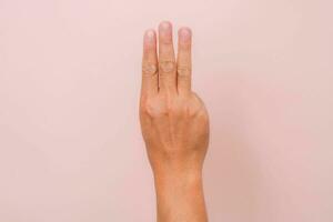 maschio mano mostrando tre dito saluto come un' simbolo per protestare contro dittatore nel asiatico nazione. uomo mano cartello isolato su rosa sfondo foto