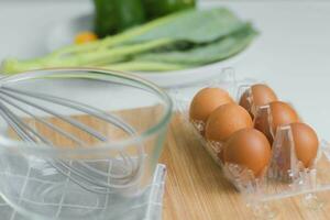 fresco biologico uova con cucina utensili su di legno sfondo. cucinare nel il cucina. preparazione prima colazione a partire dal azienda agricola prodotti, naturale uova. foto