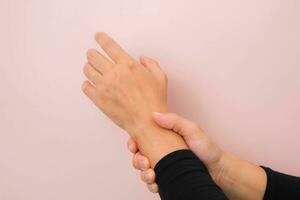 avvicinamento di donna di mano Tenere sua doloroso polso a partire dal artrite o carpale tunnel sindrome isolato su rosa sfondo. Salute cura concetto. foto