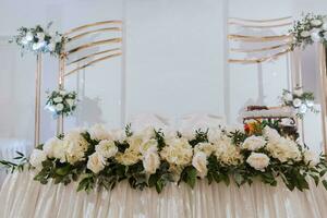 il bridal tavolo, prisidi, decorato con rosa fiori su un' bianca sfondo. preparazione per il nozze celebrazione foto