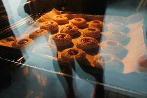 Immagine di fatti in casa appena al forno cupcakes nel un' chiuso elettrico forno. stile di vita, cottura al forno e la spesa tempo a casa concetto. foto