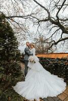 lunghezza intera ritratto di il sposa e sposo nel il giardino vicino alto alberi. nozze camminare nel il giardino foto