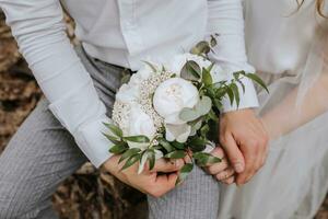 il sposa e sposo delicatamente hold mani. essi siamo Tenere un' mazzo di peonie. avvicinamento foto