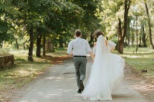 un' nozze coppia, un' contento sposa e sposo siamo in esecuzione nel il parco per il posto di il nozze cerimonia. nozze concetto foto