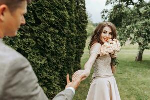 sposo e sposa nel il parco nel natura, verde thuja alberi su il sfondo. bacio. foto ritratto. nozze coppia