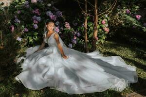 giovane bellissimo sposa nel senza spalle nozze vestito vicino ortensia fiori, moda foto prese sotto morbido luce del sole