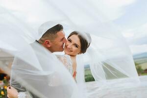 nozze coppia su natura. sposa e sposo abbracciare sotto il velo a nozze. foto