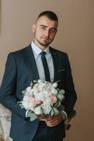 fiducioso elegante bello tipo nel un' simpatico buio blu completo da uomo con un' mazzo di fiori nel il suo mani. il sposo è preparazione per il nozze cerimonia foto
