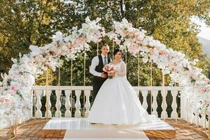 contento sposa e sposo a il nozze cerimonia. il nozze arco è decorato con rosa fiori foto