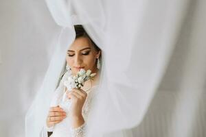 femmina bellezza. carino donna a casa. il sposa pose sotto un' velo. un' elegante donna indossa un' bianca vestire. professionale trucco e capelli. su il della sposa testa è un' corona e un' lungo velo. foto