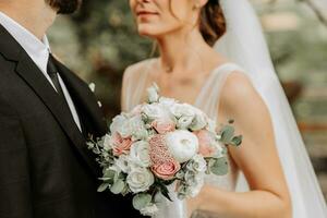 un' mazzo di fiori avvicinamento nel il mani di il sposa e sposo foto