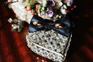 quello dello sposo Accessori nel il mattina. oro nozze anelli, nero camicia gemelli, arco cravatta foto