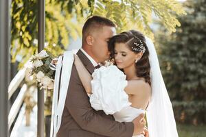 bellissimo sposa nel un' elegante nozze vestito abbraccia il sposo all'aperto nel il tramonto luce, nozze, matrimonio, relazione, stile di vita foto