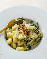 Gnocchi pasta con spinaci, parmigiano formaggio e Noci foto