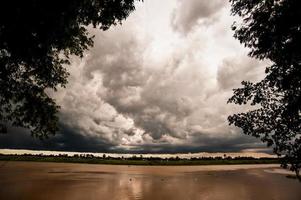 il bellissimo paesaggio del cielo nuvoloso con fiume e alberi durante il crepuscolo foto