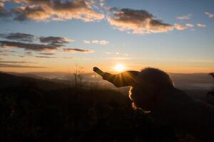 silhouette di mano femmina che tiene la luce del sole foto