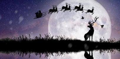 sagoma di babbo natale che sorvola la luna piena. foto