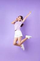 giovane ragazza asiatica che salta su sfondo viola foto