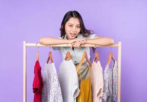 immagine di una donna alla moda in gonna in piedi vicino all'armadio con i vestiti e che sceglie cosa indossare isolato su sfondo viola foto