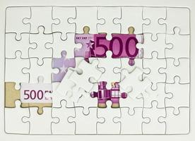 Pezzi mancanti del puzzle su cinquecento 500 banconote in euro sullo sfondo delle banconote, concetto di soluzione aziendale, chiave per il concetto di successo foto