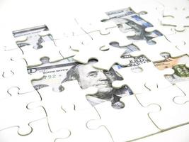 pezzi mancanti del puzzle su sfondo di denaro da 100 dollari, chiave per il concetto di successo della soluzione aziendale foto