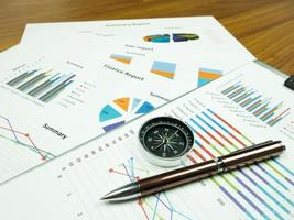 grafico del rapporto aziendale e analisi del grafico finanziario con penna e bussola sul tavolo foto