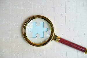 ingrandimento bicchiere e su il mancante puzzle pezzo. foto illustrazione concetto di ricerca per e reclutamento nuovo dipendenti