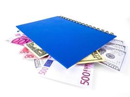 libro blu con banconote internazionali nidificate, isolato su sfondo bianco. scorta di denaro concetto, idee imprenditoriali foto